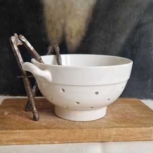 Könnte beinhalten: Eine weiße Keramik-Tasse mit schwarzem Henkel und dem Text "But First, Coffee" in schwarzer, fetter Schrift. Die Tasse steht auf einer weißen Oberfläche. Die Tasse scheint leer zu sein.