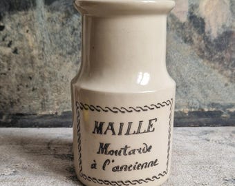 May include: A white ceramic jar with a black label that reads "Maille Mustard à l'ancienne".