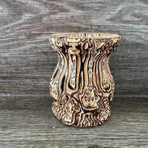 Puede incluir: Un jarrón de cerámica con un patrón abstracto marrón y blanco. El jarrón tiene una base ancha y un cuello estrecho.