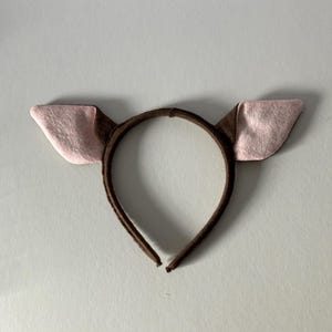 Peut inclure: Un serre-tête marron avec deux oreilles dressées. Les oreilles sont marron à l'extérieur et roses à l'intérieur. Le serre-tête est en matière souple, idéal pour les fêtes costumées ou les événements à thème.