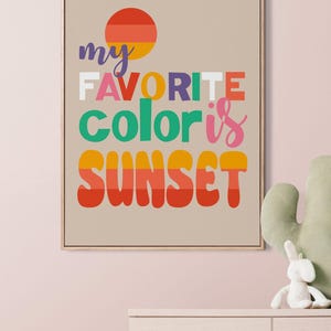 May include: Framed art print with the text "my FAVORITE color is SUNSET" in colorful, bold letters. The artwork features a sunset graphic and is displayed on a neutral background. A decorative piece for a nursery or bedroom.