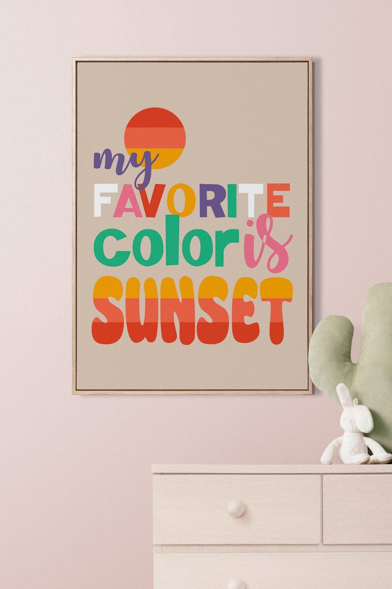 May include: Framed art print with the text "my FAVORITE color is SUNSET" in colorful, bold letters. The artwork features a sunset graphic and is displayed on a neutral background. A decorative piece for a nursery or bedroom.