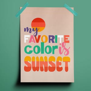 May include: A beige poster with the text "my FAVORITE color is SUNSET" in colorful, retro-style lettering. A circular graphic of a sunset is at the top. The poster is taped to a green background with blue tape.