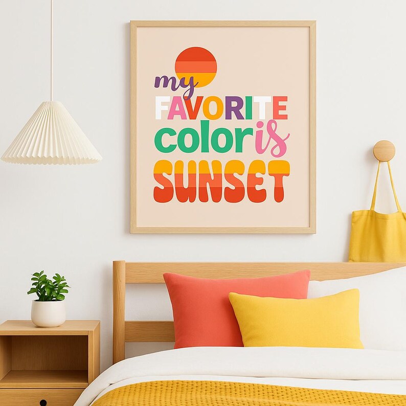 May include: A framed print with the text "my FAVORITE color is SUNSET" in colorful, retro-style lettering. The artwork features a stylized sunset graphic and is displayed above a bed with orange and yellow pillows.