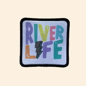 May include: A colorful embroidered patch with the text "River Life" in a playful font. The patch has a black border and a white background.