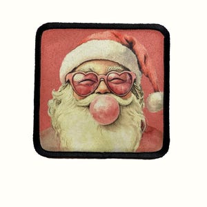 May include: A red and white Santa Claus with a pink bubblegum in his mouth and pink heart-shaped sunglasses. The background is a red color.