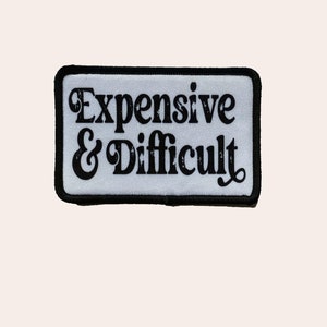 May include: White patch with black border and text that reads "Expensive & Difficult" in a retro font.