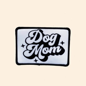 May include: White patch with black border and text "Dog Mom" in a retro font with stars on either side.