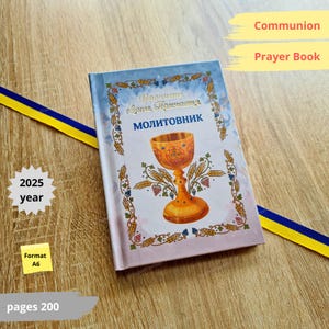Può includere: Un libro di preghiere per la Comunione con un'illustrazione di calice dorato, il testo "MOLITOVNIK" e altro testo in lingua straniera. Il libro ha una copertina blu e oro con decorazioni floreali. L'anno 2025 è stampato sulla copertina. Formato A6, 200 pagine.