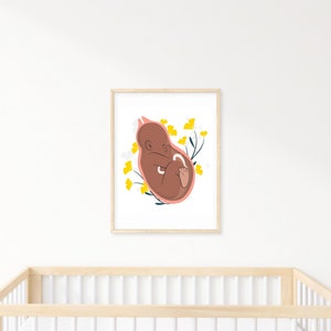 May include: A framed art print featuring a stylized illustration of a fetus in a womb. The artwork uses a warm color palette with a brown fetus, a pink womb outline, and yellow floral accents. The print is displayed above a wooden crib.