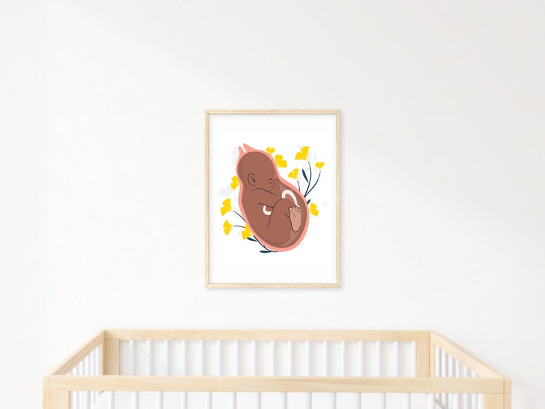 May include: A framed art print featuring a stylized illustration of a fetus in a womb. The artwork uses a warm color palette with a brown fetus, a pink womb outline, and yellow floral accents. The print is displayed above a wooden crib.