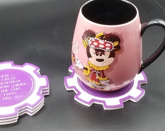 Könnte beinhalten: Lila und weiße Untersetzer in Zahnradform mit dem Text "Here's to a Great Day!  Be a better you tomorrow.  Think about how you're going to be at the end of every day."  Eine rosa Tasse mit einem Cartoon-Bild von Minnie Mouse, die eine Schlafmaske und einen Pyjama trägt, steht auf einem der Untersetzer.