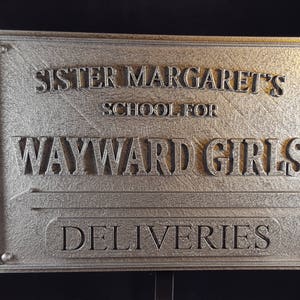 May include: A silver metal sign with the text "Sister Margaret's School for Wayward Girls" and "Deliveries" on it.
