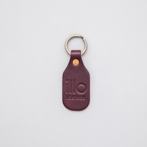 Purple key tag with Illo Leather logo on a light grey background