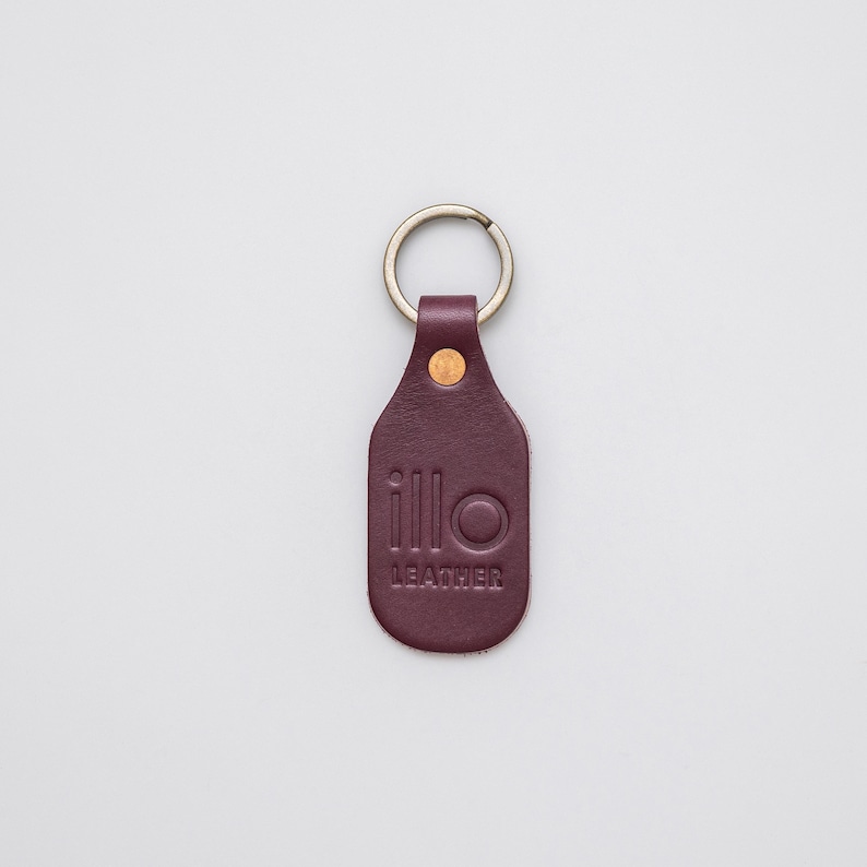 Purple key tag with Illo Leather logo on a light grey background