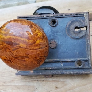 May include: Antique door knob with a brown and gold marbled ceramic knob and a black metal base.
