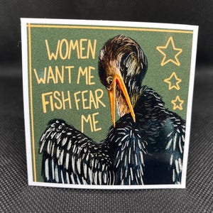 May include: Square sticker with a green background and a drawing of a bird with a long beak. The text reads "WOMEN WANT ME FISH FEAR ME" in yellow letters. Three yellow stars are also on the sticker.