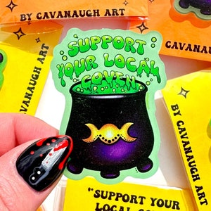 May include: A yellow and green acrylic pin with a cauldron and the text "Support Your Local Coven".
