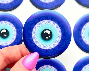 May include: A set of seven blue and white evil eye stickers with a mandala design. The stickers are round and have a white background with a blue evil eye in the center. The evil eye is surrounded by a white mandala design.