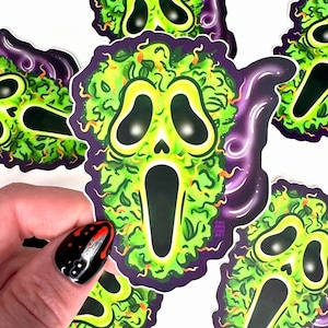 May include: Five green and purple stickers with a ghost face design. The ghost face is made of green leaves and has a white scream. The stickers are on a white background.