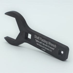 May include: A black shaft packing wrench with text that reads "Shaft Packing Wrench" and "Tighten until 1 drip every 10 seconds". The wrench has a square opening and a curved end. The text "York Design and Fabrication, LLC" is also visible.