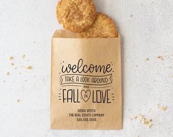 May include: A brown paper bag with a welcome message that says "welcome, take a look around and fall in love". The bag is filled with two cinnamon sugar cookies.