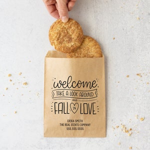 May include: A brown paper bag with a welcome message that says "welcome, take a look around and fall in love". The bag is filled with two cinnamon sugar cookies.