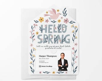 May include: A white card with a floral design and the text "HELLO SPRING" in blue. The card has a cut-out for a business card with a photo of a woman and the text "Harper Thompson, REAL ESTATE AGENT" and "Market Dwellings".