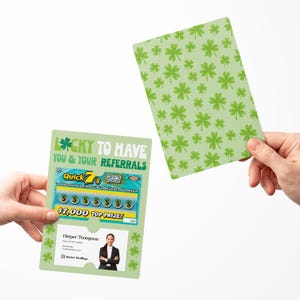 May include: A green card with a shamrock design and the text "Lucky to have you & your referrals". The card has a scratch-off lottery ticket attached with the text "Quick 7's" and a top prize of $7,000. A business card with a photo of a woman is visible in the window.