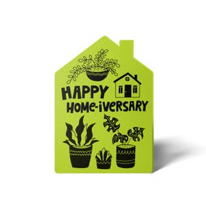 May include: A green house-shaped card with the text "HAPPY HOME-IVERSARY" and black illustrations of potted plants and a house.