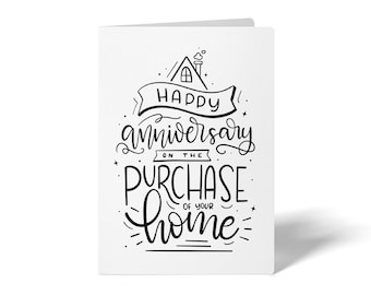 May include: A white card with black text that reads "Happy anniversary on the purchase of your home". The text is in a handwritten style and includes a small house illustration with a chimney.