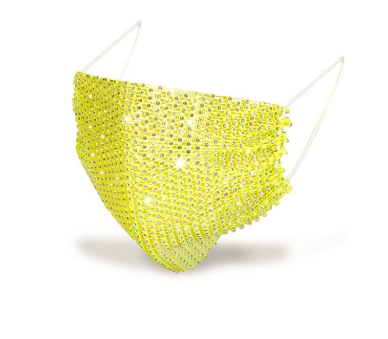 May include: A yellow face mask covered in rhinestones. The mask has a simple design and is made of a soft, flexible material.