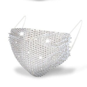 May include: A white face mask covered in rhinestones. The mask has a simple design with two straps that tie behind the head.