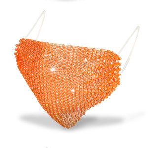 May include: Orange face mask made of rhinestones. The mask is designed to cover the nose and mouth.