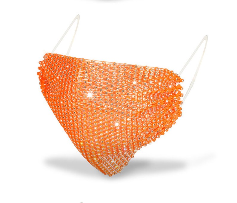 May include: Orange face mask made of rhinestones. The mask is designed to cover the nose and mouth.
