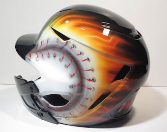 May include: A black and white baseball helmet with a baseball design. The helmet has a glossy finish with red stitching details and a fiery orange and yellow gradient design on the side.