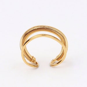 May include: A gold-toned ring with a double-coil design. The ring is open and adjustable.