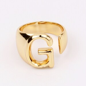 May include: Gold-toned ring with a large letter G cutout. The ring is open on one side and has a smooth, rounded finish.