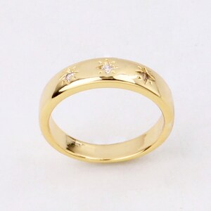 May include: A gold band ring with three small star-shaped diamonds.