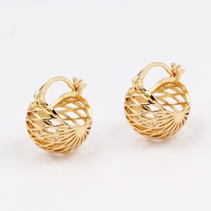 May include: A pair of gold hoop earrings with a delicate, geometric design. The earrings are made of a thin, wire-like material that creates a circular shape with a sunburst pattern.
