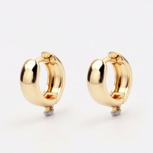 May include: A pair of gold hoop earrings. The earrings are simple and classic, with a smooth, polished finish.