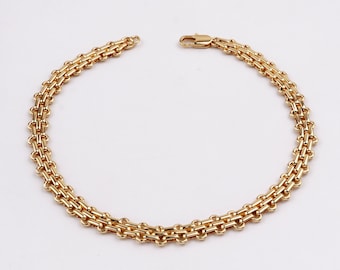 May include: A gold chain bracelet with a delicate, interwoven design. The bracelet is made of a single strand of chain that is linked together in a repeating pattern.