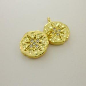 Pu&ograve; includere: Due ciondoli in metallo dorato con un design a stella e strass trasparenti. I ciondoli sono collegati da un anello.