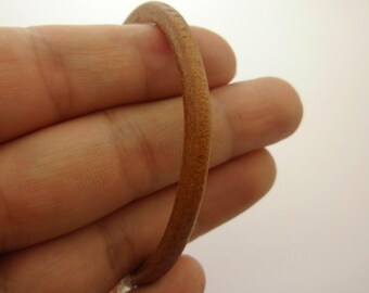 May include: A close-up of a brown leather cord, showing the texture and detail of the leather.