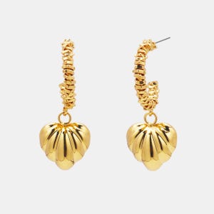 Peut inclure: Une paire de boucles d'oreilles dorées. Chaque boucle d'oreille présente un design en forme de cercle avec un aspect texturé en forme de chaîne. Un charm en forme de cœur avec des rainures verticales est suspendu à chaque cercle.