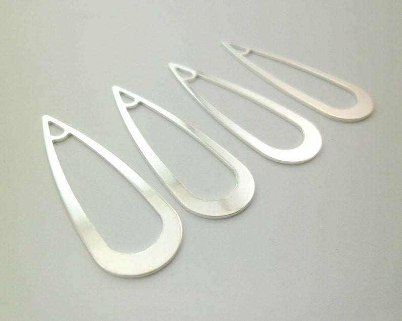 May include: Four silver teardrop-shaped earring blanks with a hole at the top.