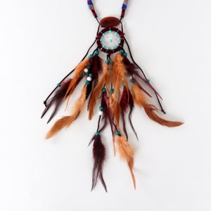 May include: A brown and white dreamcatcher necklace with turquoise beads and brown feathers.