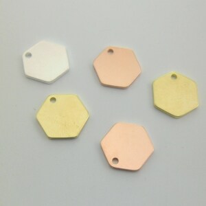 Può includere: Cinque ciondoli esagonali in metallo color argento, oro e oro rosa.