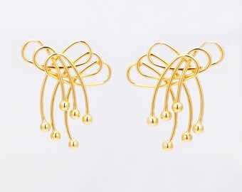 May include: A pair of gold-toned earrings with a delicate, abstract design. The earrings feature multiple interconnected loops and small round beads.