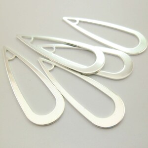 May include: Five silver-toned metal teardrop-shaped earring blanks with a hole at the top.